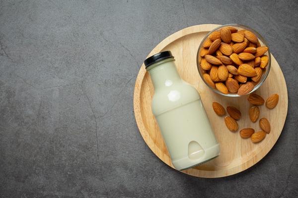 almond milk in bottle with almond on dark background - Овсянка с ягодами и миндалём без варки