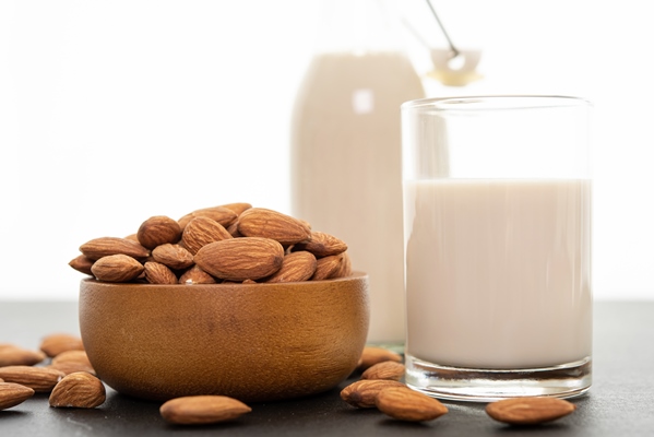 almond milk with almond in a wooden bowl on black background - Овсянка кремовая с тахини