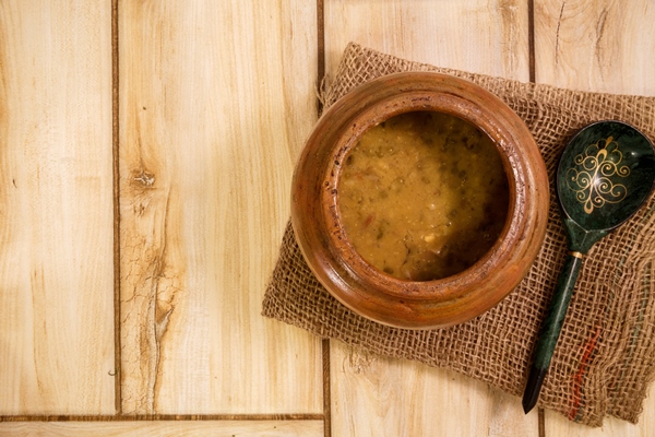 bean soup in a traditional pot on a wooden table view from above - Монастырская кухня: фасолевый суп с орехами, банановый рулет (видео)