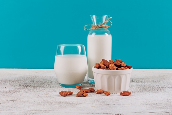 bottle of milk with glass of milk and bowl of almonds side view on a white wooden and blue background - Постная "окрошка" с водорослями
