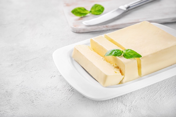 cut block of fresh butter in white ceramic butter dish on white - Морковная бабка