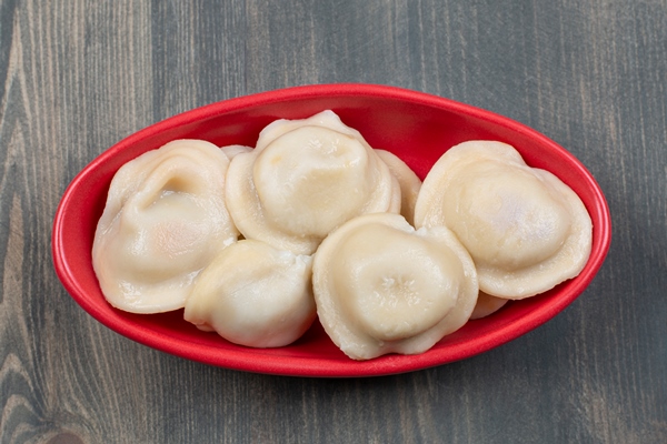 delicious dumplings in a red plate on a wooden table - Монастырская кухня: вареники с яблоком и изюмом, морковное печенье