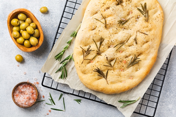 freshly baked italian traditional homemade focaccia bread baking with seasonings and rosemary on parchment paper and light gray wall top view - Щи постные богатые и фокачча (видео)