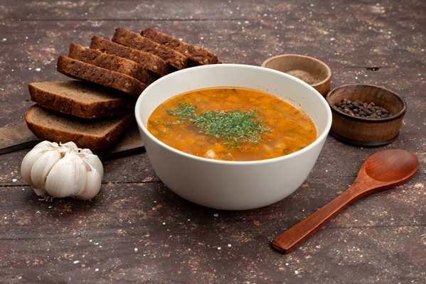 front view orange vegetable soup with bread loafs and garlic on brown food meal soup - Монастырская кухня: луковый суп с редькой, тыквенные оладьи