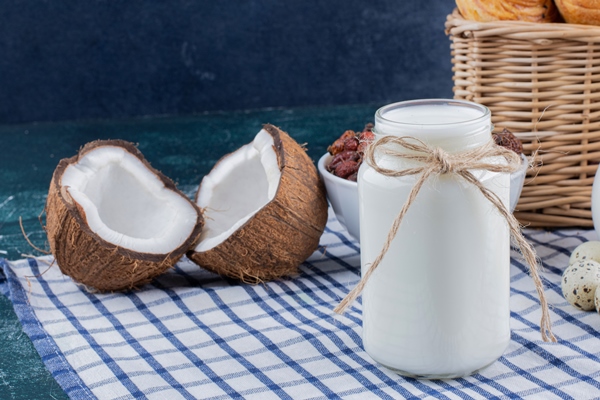 glass jar of milk and half cut coconuts on marble table - Овсянка с манго, бананом и чиа