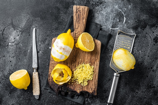 grated lemon zest and spiral peel on wooden board black background top view - Монастырская кухня: рис с баклажанами, ревани