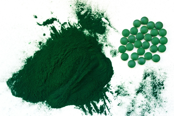 green hawaiian spirulina in tablespoons pills and powder on light white background - Постный салат с пророщенным машем