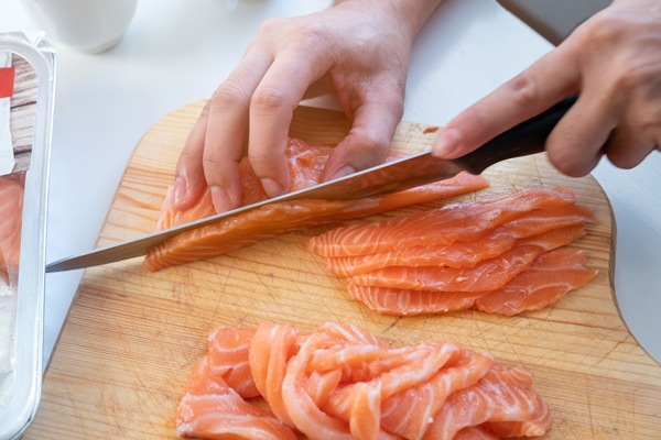 hand cook using knife slicing a fresh salmon on wooden chopping block - Монастырская кухня: архиерейская солянка, постный "Наполеон" (видео)