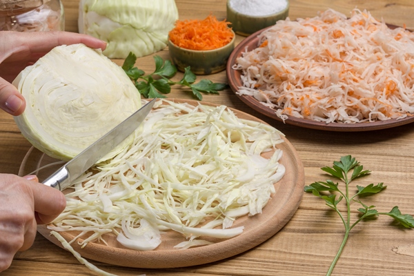 hands chop slice raw cabbage half cabbage head sauerkraut in plate homemade fermentation products close up - Монастырская кухня: луковый суп с капустой, свекольные котлеты (видео)