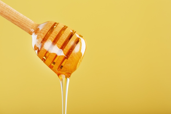 honey drips in a thin stream from a honey dipper on a yellow background - Монастырская кухня: печенье маковое с карамелью, морковный суп-пюре (видео)