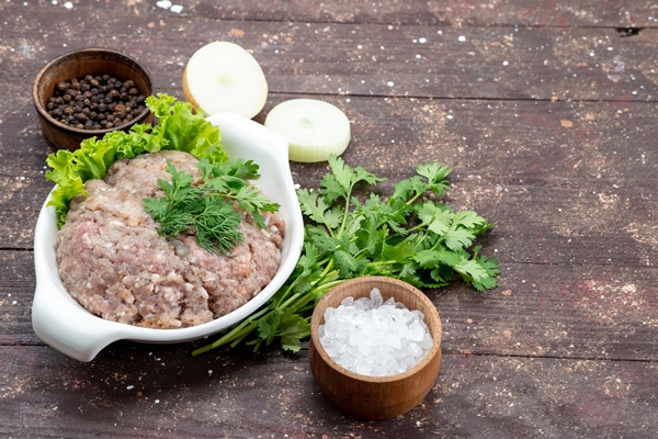 minced raw meat with greens inside plate with onions salt on brown - Голубцы мясные