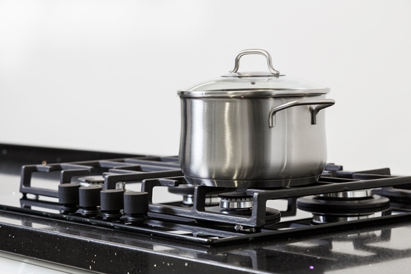 new iron pot on a black gas stove on a kitchen - Овсянка с малиной и кешью без варки