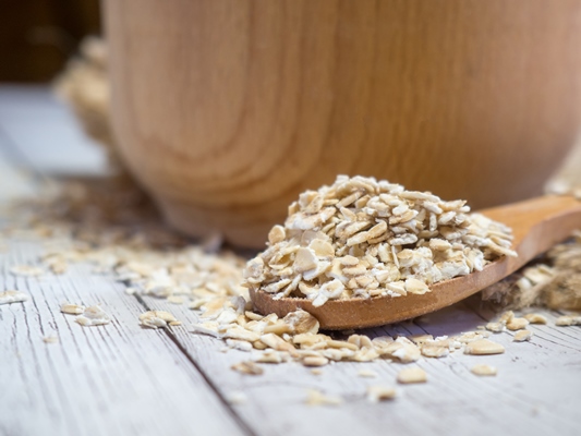 oatmeal in a wooden bowl and spoon on a wooden table close up - Монастырская кухня: печенье на томатном соке, овсяный суп с цветной капустой