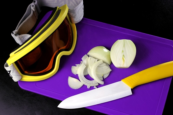 onion sliced on a cutting board with a yellow handled knife and a ski mask - Монастырская кухня: овсянка с луком и изюмом, квашеная капуста (видео)