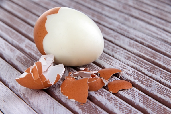 peeled boiled egg on wooden background - Блинчатый пирог с грибами