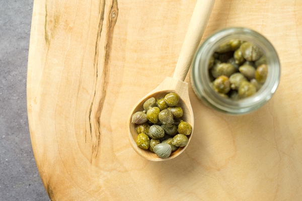 pickled or marinated green capers on a wooden spoon close up selective focus 1 - Шницель