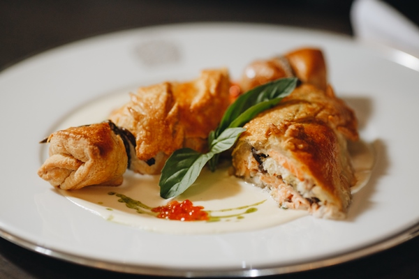 pie with sauerkraut and fish russian kulebyaka on a white plate and a wooden table behind a brown tablecloth side view at an angle close 1 - Кулебяка из дрожжевого теста