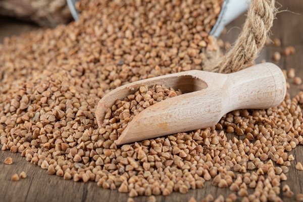 pile of uncooked buckwheat on wooden spoon - Гречнево-кокосовая каша без варки