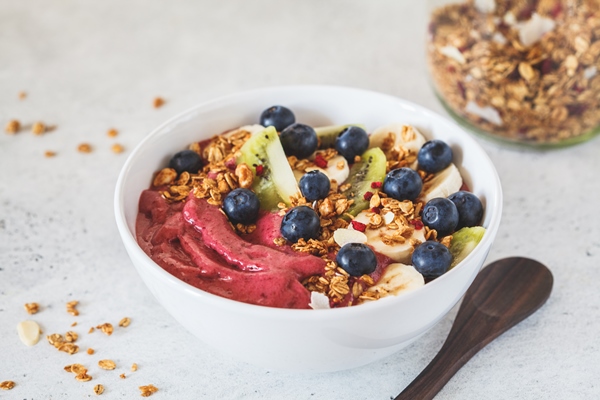 pink berry smoothie bowl with fruits berries and granola in white bowl on white - Монастырская кухня: манный мусс с клюквой и расстегаи