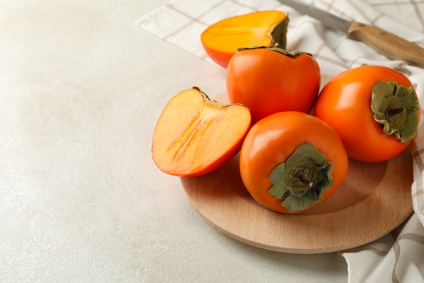 plate with persimmon knife and kitchen towel on white table - Овсянка с хурмой и тыквой без варки