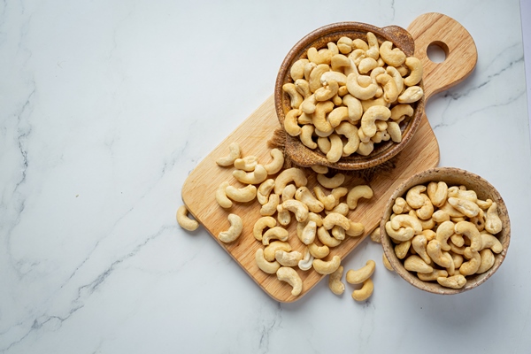 raw cashews nuts in bowl on marble background - Овсянка с малиной и кешью без варки