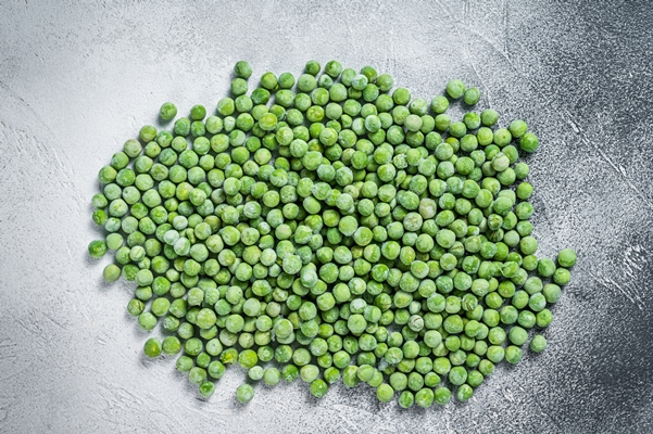 raw frozen green peas on kitchen table white background top view - Монастырская кухня: овсянка с горошком, томатный суп с фасолью (видео)