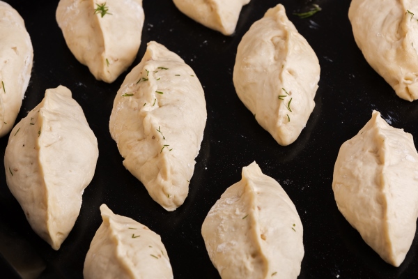 raw pasty patties lying on a baking tray and ready for baking close up view - Монастырская кухня: чечевичный суп с квашеной капустой, жареные пирожки с капустой