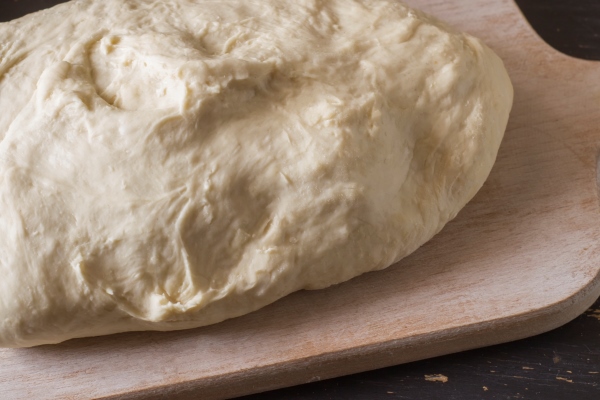 raw unleavened dough for dumplings on a wooden table - Монастырская кухня: вареники с яблоком и изюмом, морковное печенье