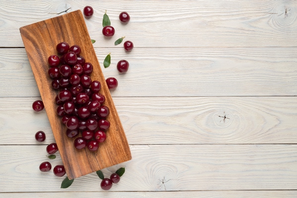 ripe cherries and leaves in a wooden plate on a textured wooden background view from above - Блинный торт "Монастырская изба"