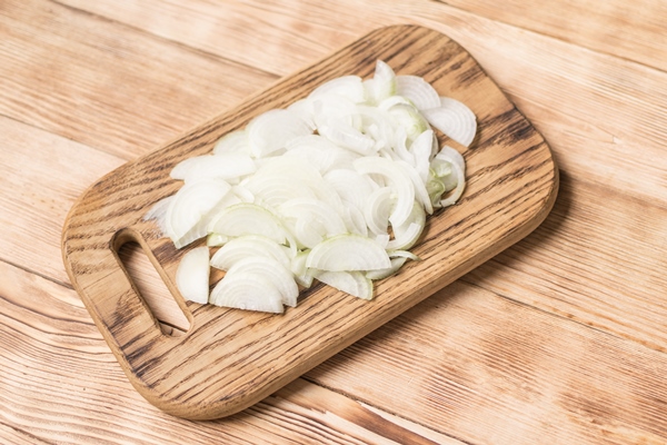 sliced onions with half rings on a wooden chopping board on a wooden background - Луковый соус без варки