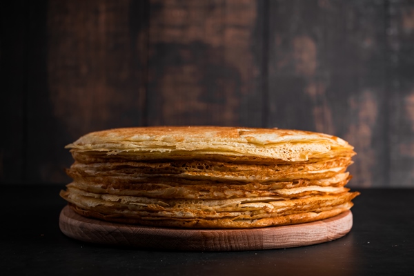 stack of thin pancakes on dark wooden background traditional dish of crepes for holiday maslenitsa - Блинчики с сыром и яйцом