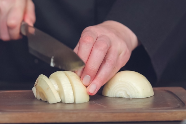 step by step dicing yellow onion on a wood cutting board - Лапша с поджаркой из овощей и сейтана (клейковины)