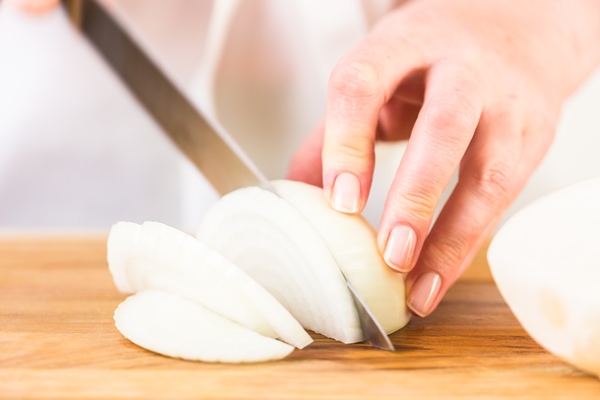 step by step slicing yellow onion with kitchen knife on a cutting board - Монастырская кухня: рис с баклажанами, ревани