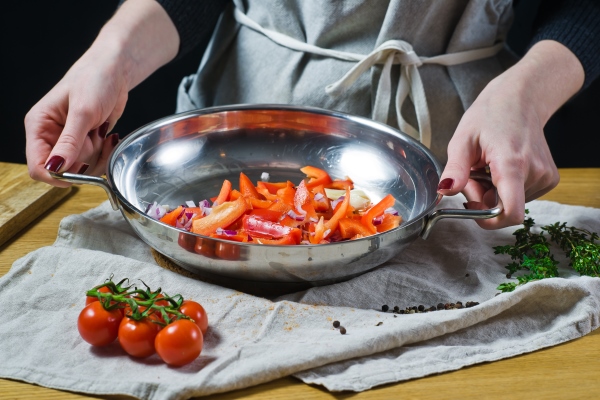 the chef puts chopped red bell peppers and onions with a knife in the pan - Монастырская кухня: тёплый салат из зелёной фасоли и каша-мешанка (видео)