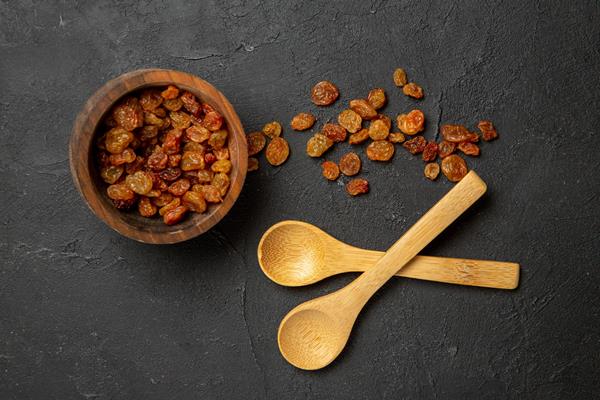 top view dried grape raisins with wooden spoons on dark surface dry fruit raisin - Монастырская кухня: вареники с яблоком и изюмом, морковное печенье