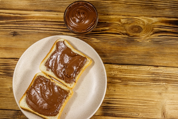 two slices of bread with delicious chocolate hazelnut spread on wooden table top view - Паста из грецких орехов