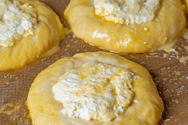 vatrushka laid out on baking paper before being sent to the oven the concept of homemade cakes - Сдобные ватрушки