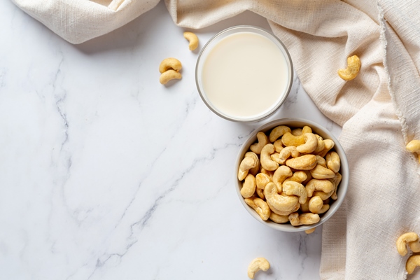 vegan cashew milk in glass with cashews nuts on marble background - Овсянка с яблоком и корицей