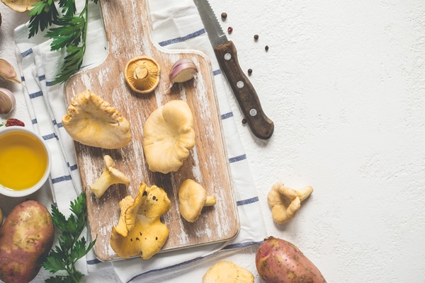 white cooking background with wild chanterelles on a cutting board spices and knife - Монастырская кухня: грибные вареники, овсяный кисель