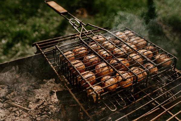 white small round mushrooms champignons stacked in even rows in a barbecue grill - Шашлык из шампиньонов