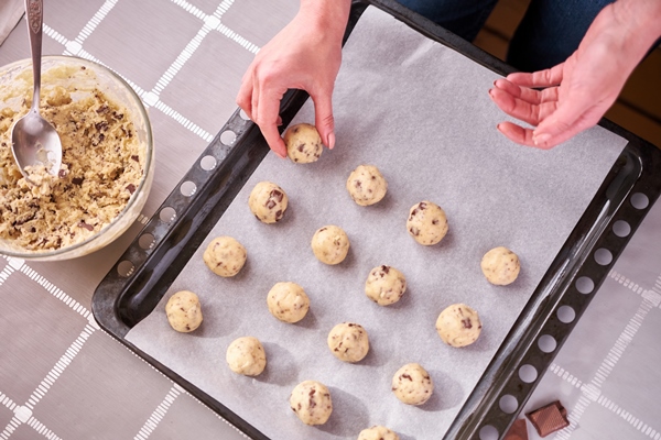 woman holding ball of raw dough while making chocolate chip cookies - Монастырская кухня: рисовые котлеты с грибным соусом, овсяное печенье