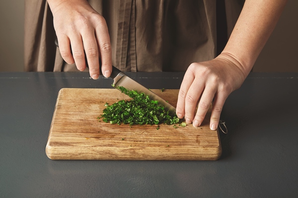 women hand chop parsley on wooden board on old blue table close up - Монастырская кухня: суп "Святогорский", печенье курабье (видео)