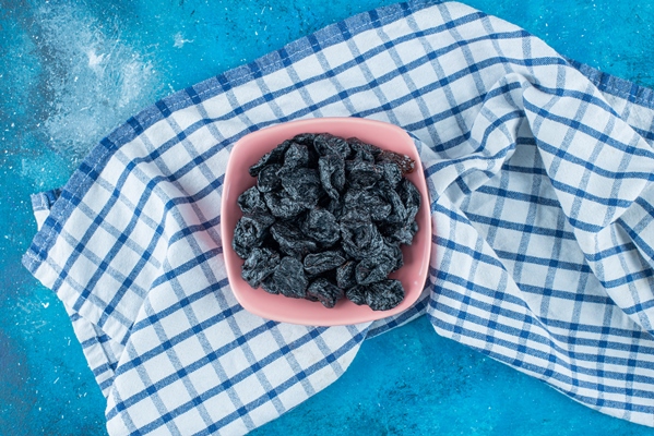 black raisins in a bowl on tea towel on the blue table - Куличи александрийские