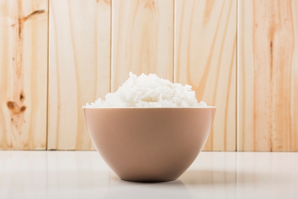 boiled white rice in the bowl on white table against wooden background - Пирог с икрой