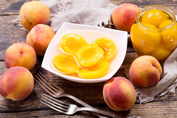 bowl of canned peaches with fresh fruits on wooden table - Особенности питания детей