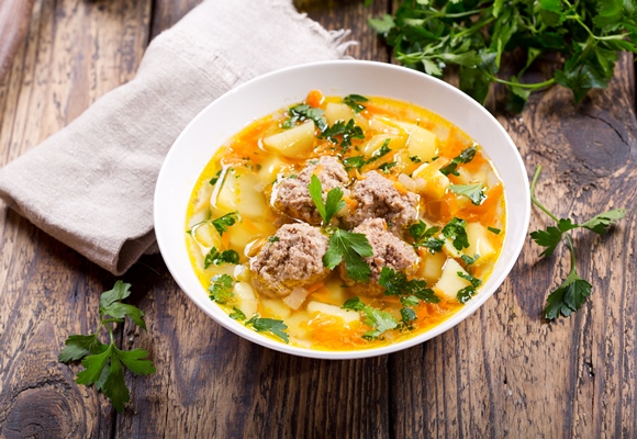 bowl of soup with meatballs and vegetables on wooden table - Мясные фрикадельки в супе