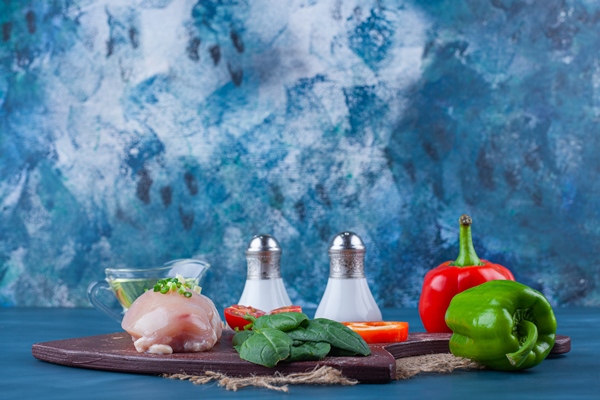 chicken breast and vegetables on a cutting board non a burlap napkin on the blue surface - Лечебное питание