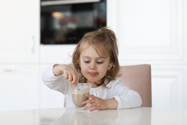 child girl in white kitchen at home drink cocoa - Особенности питания детей