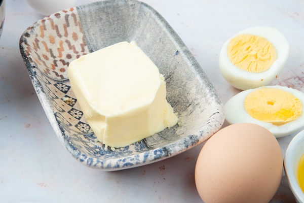 close up view of plate of butter with eggs on white background - Начинка из моркови