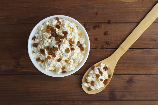 cottage cheese in a white plate with raisins stands on a brown wooden table a spoon lies nearby delicious and healthy breakfast 1 - Пасха без творога с изюмом